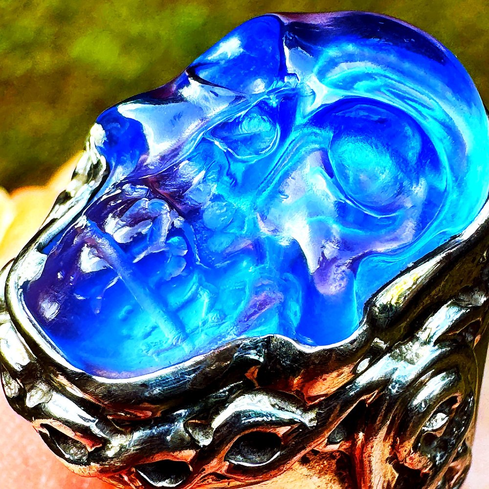 The Ashta Project sterling-silver skull ring — a carved blue Siberian-blue crystal skull set on an infinity-knot band